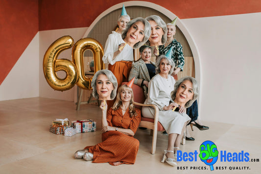 A joyful 60th birthday celebration featuring a woman holding up a large, custom face cutout of herself, designed as a BIG Heads™️. 
