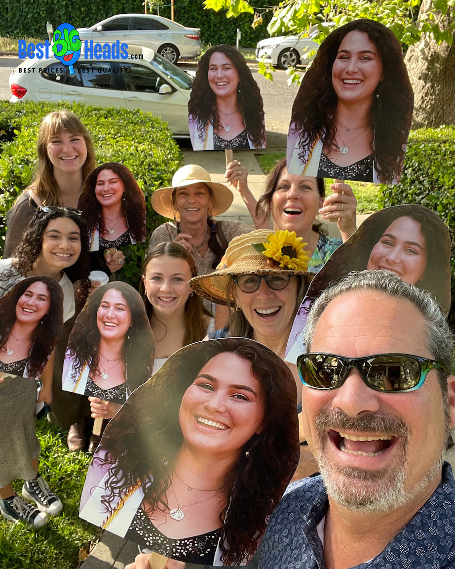 Proud family members holding a giant face cutout of their graduating loved one, celebrating with joy and excitement. 🎓🎉