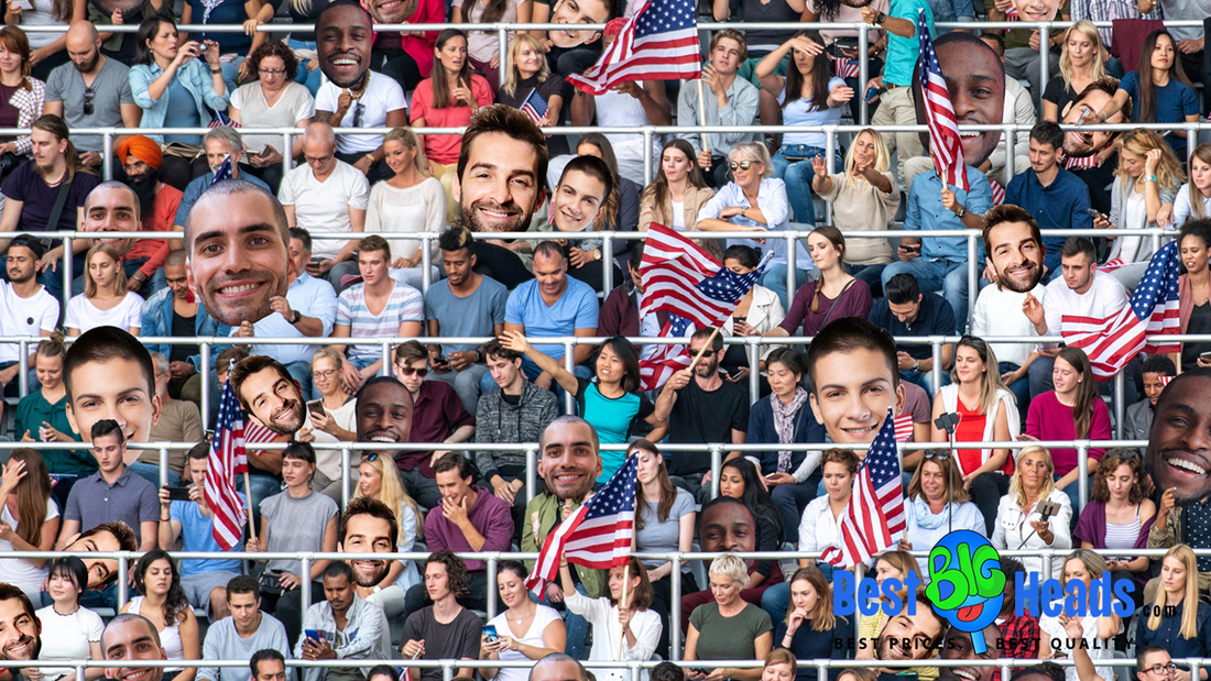 A large crowd of people sitting in bleachers holds American flags. Some individuals have oversized cutouts of faces. The sign "Best Big Heads" is at the bottom right.
