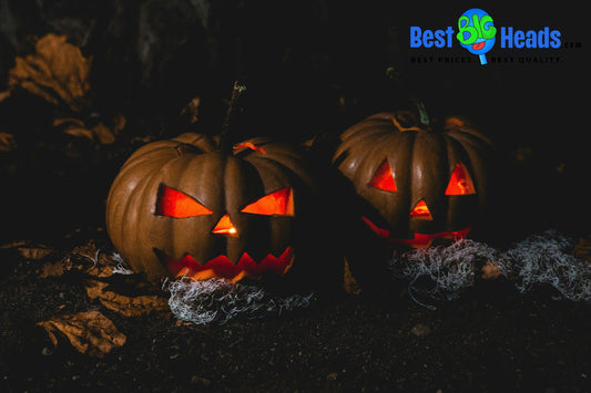 Two glowing jack-o'-lanterns with menacing faces sit on the ground in the dark, illuminated from within by flickering lights. Surrounded by dried leaves and spooky cobwebs, this scene captures the eerie atmosphere of Halloween night.