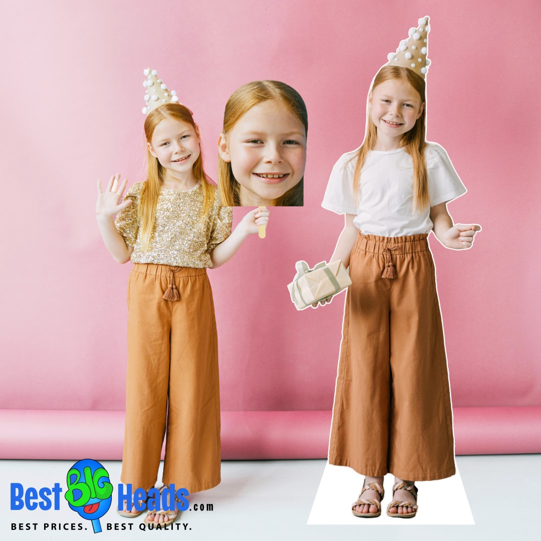 A young birthday girl smiling and posing next to her life-size standup cutout. She is wearing a festive outfit and a party hat, holding a gift in front of a pink background.